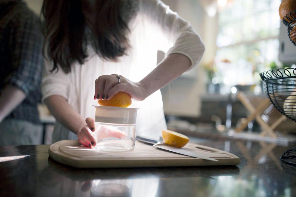 Free Image of Woman squeezing orange juice in bright kitchen 