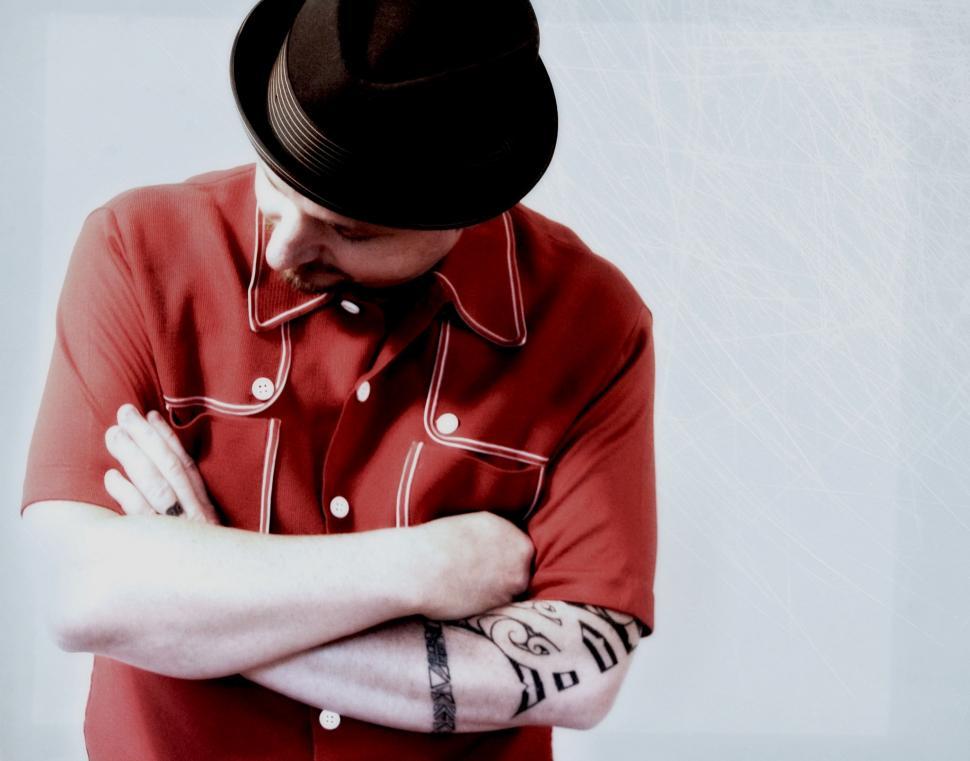Free Image of Tattooed man with crossed arms and fedora hat 