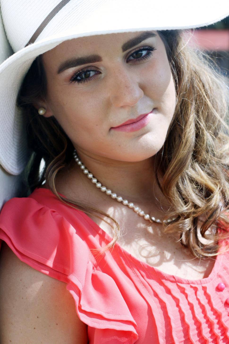 Free Image of Elegant lady with hat and pearls at an event 