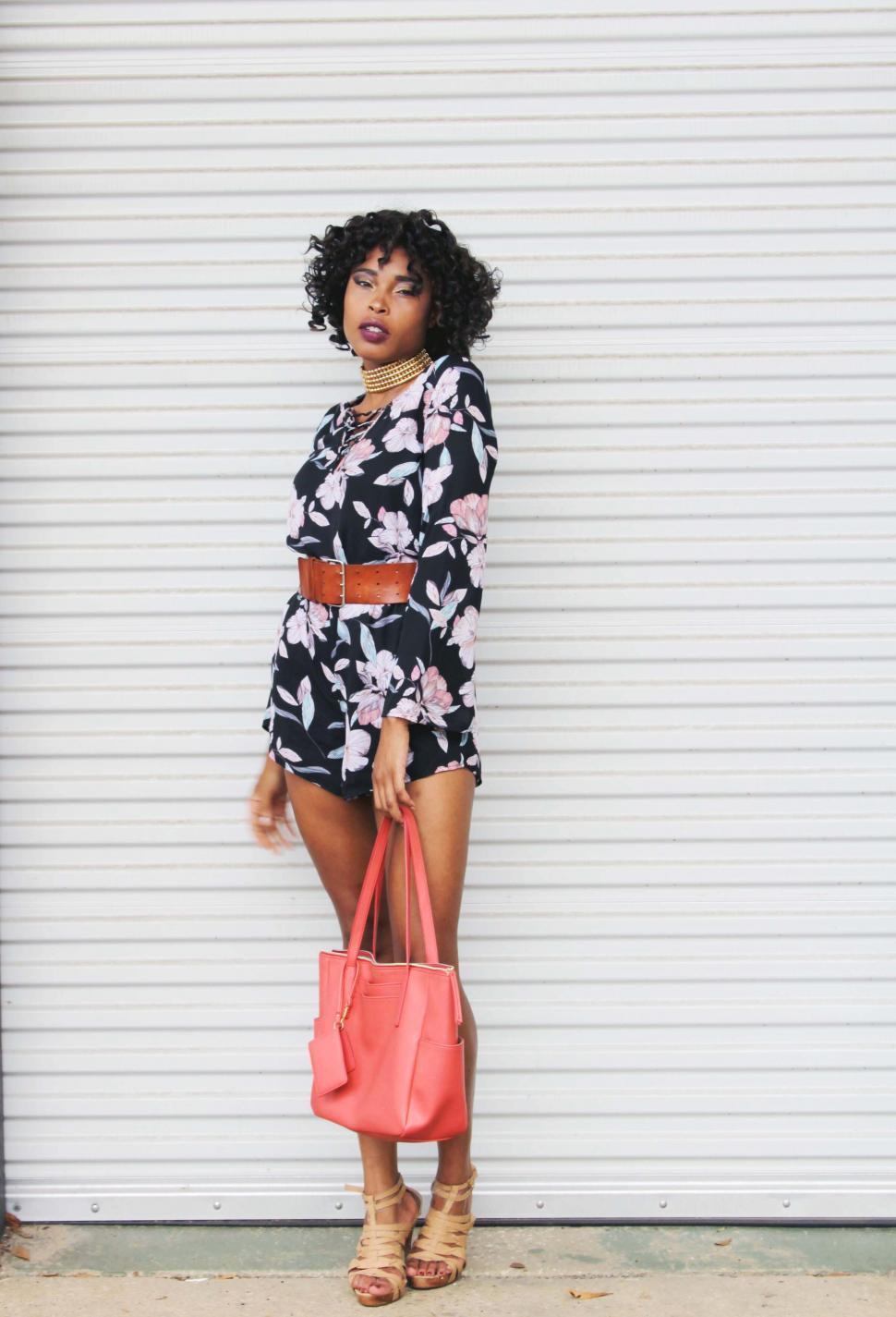 Free Image of Fashionable woman with bag standing by wall 