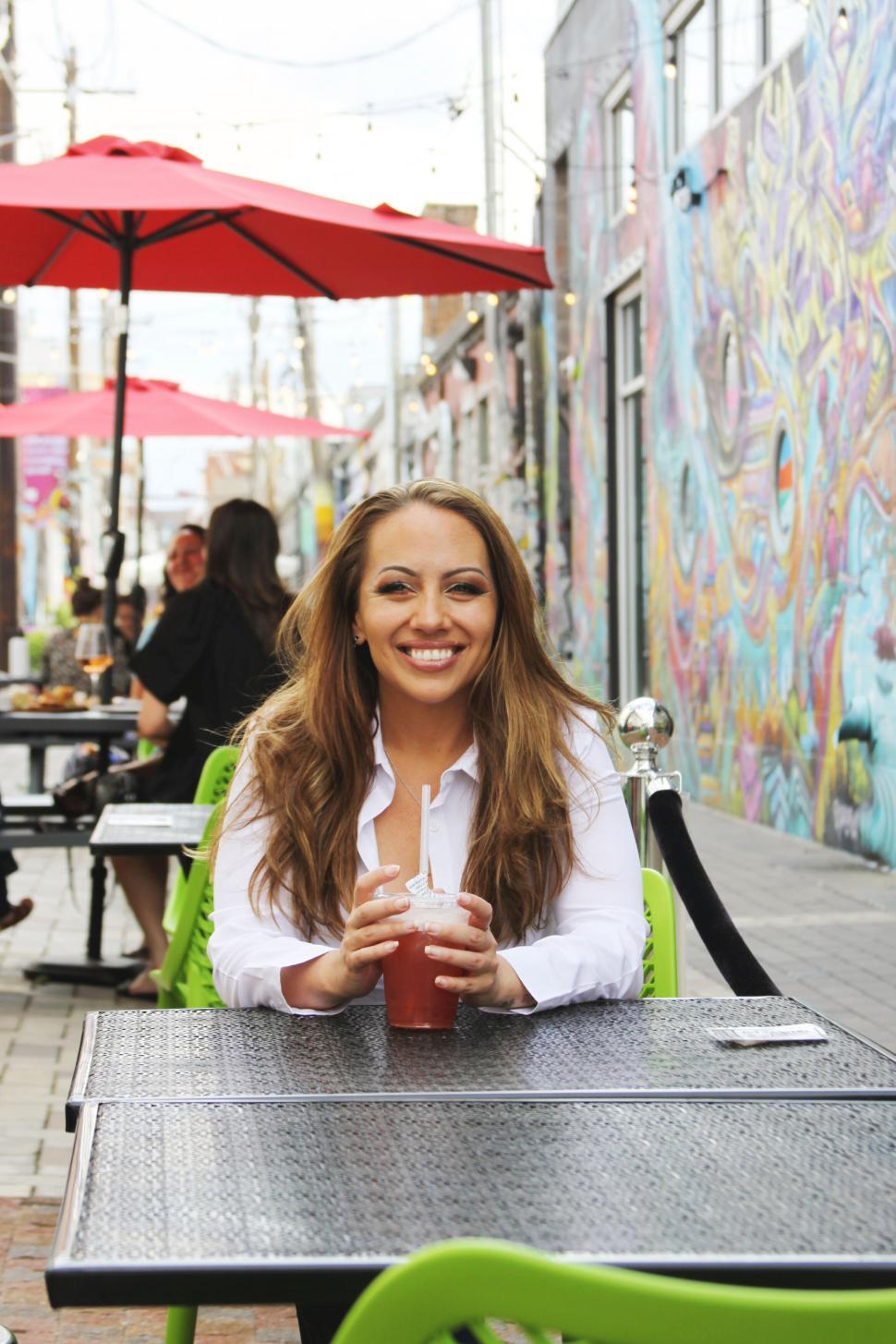 Free Image of Woman enjoying a drink at a street cafe 