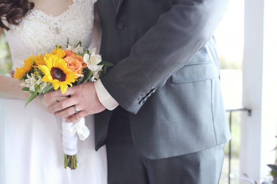 Free Image of Bride and groom holding hands with bouquet 