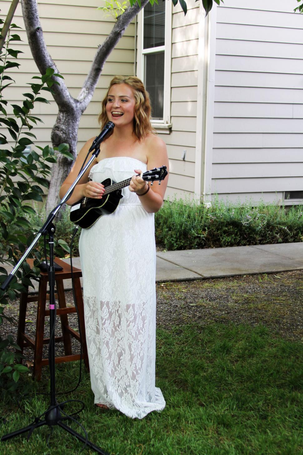 Free Image of Woman in white dress playing ukulele 
