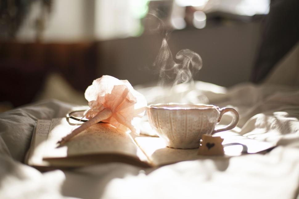 Free Image of Steaming tea cup with open book 