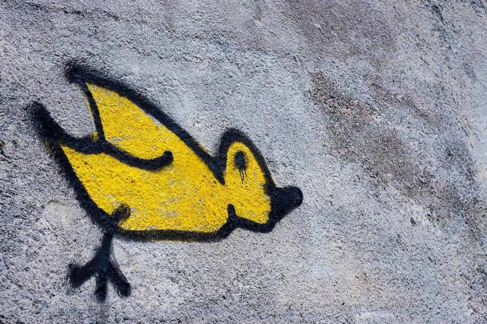 Free Image of Yellow bird graffiti on a textured wall 