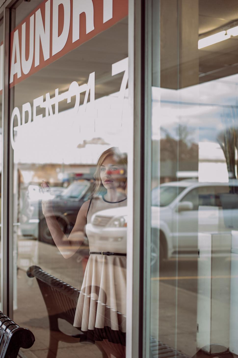 Free Image of Woman gazing out of a laundry shop window 
