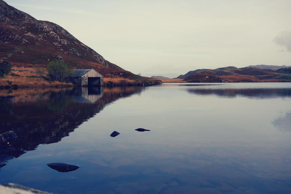 Free Image of Serene lakeside view with a small cabin 
