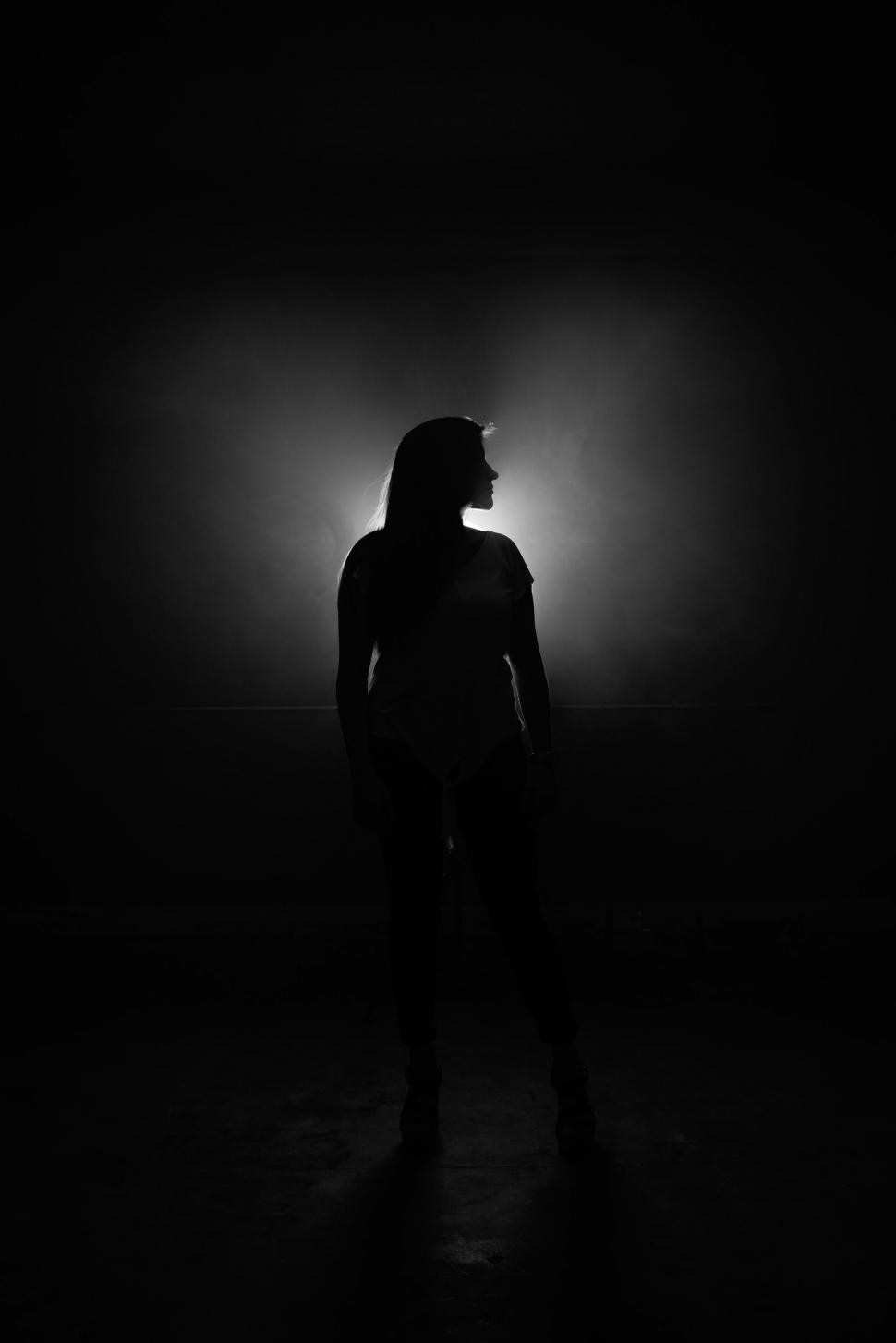Free Image of Silhouetted woman standing against bright light 