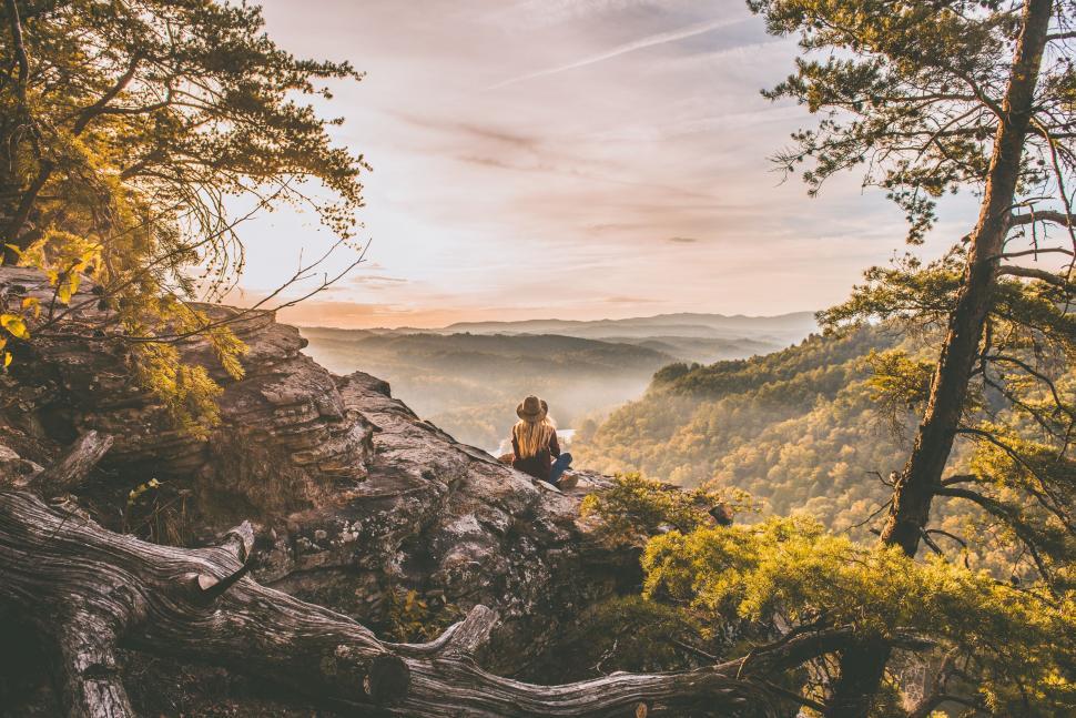 Free Image of Person sitting on cliff overlooking sunset 