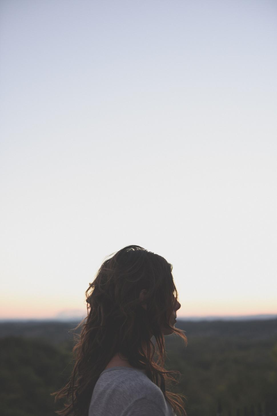 Free Image of Woman with long hair watching sunset obscured 