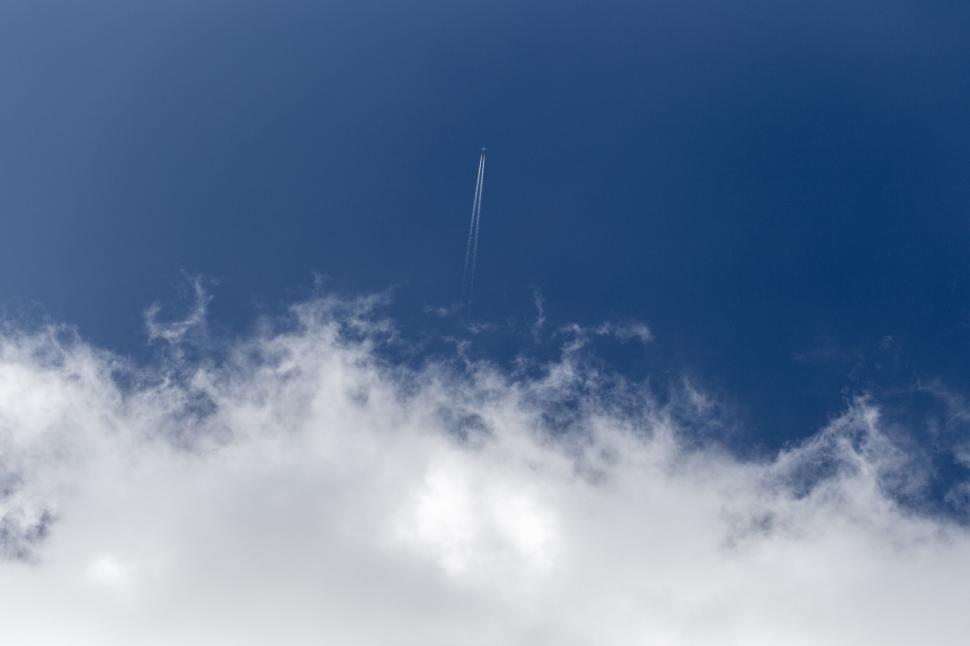 Free Image of Airplane flying high in a blue sky with clouds 