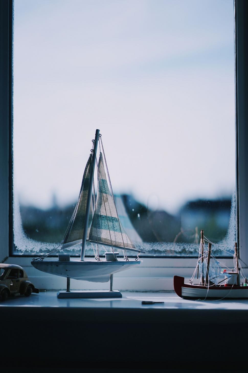 Free Image of Sailboat models on windowsill with rainy view 