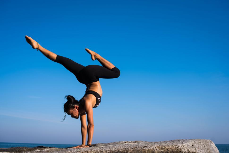 Free Image of Woman practicing yoga on seaside rock 