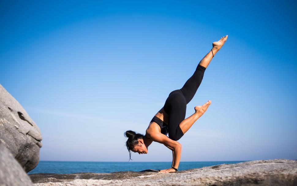 Free Image of Woman performing yoga on a rocky beach 