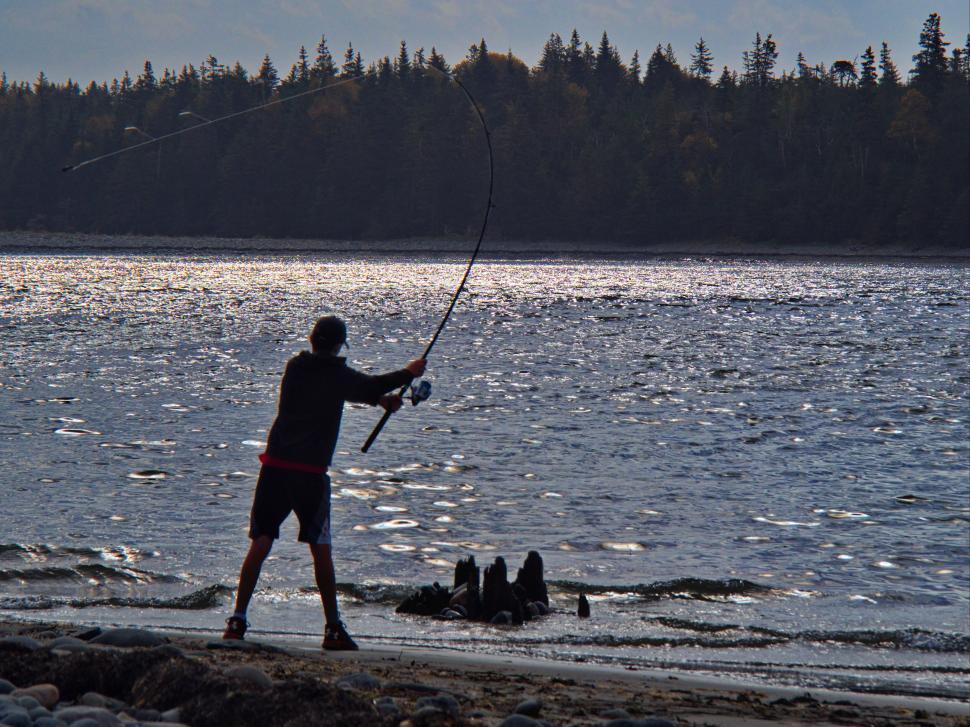 Free Image of Silhouette of a man fishing at sunset 
