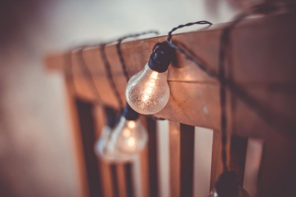 Free Image of Warm light bulb on rustic wooden railing 