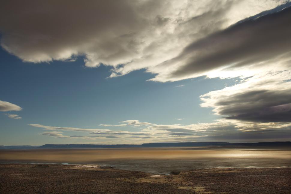Free Image of Expansive lake landscape under a cloud-filled sky 