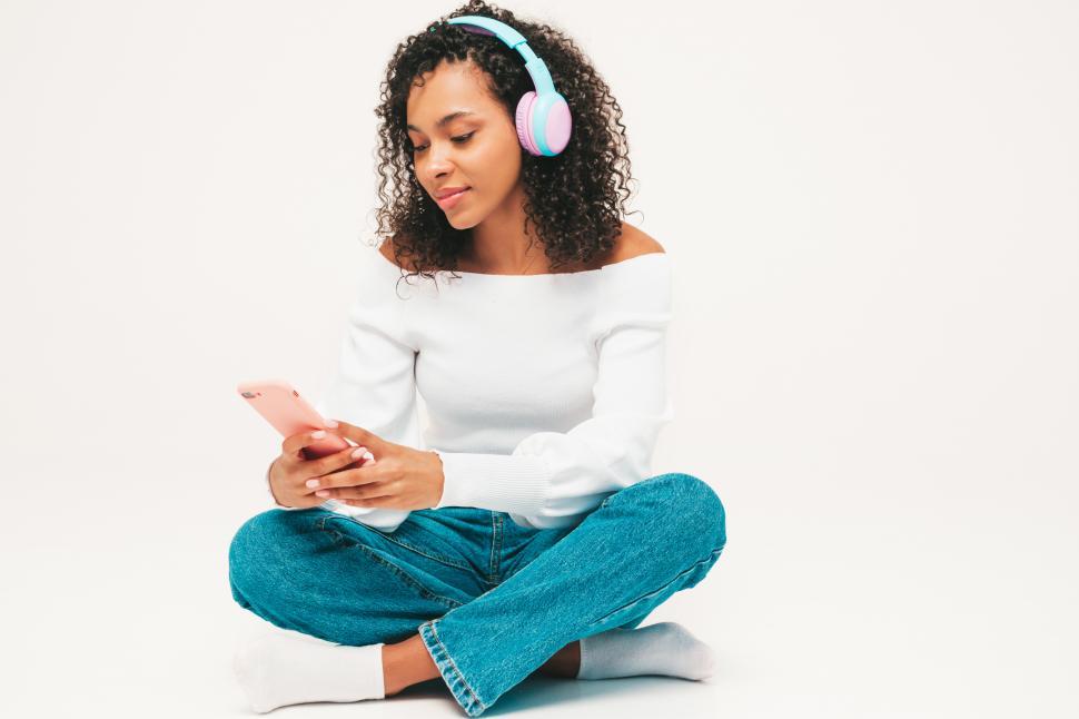 Free Image of A woman sitting cross legged with headphones on 