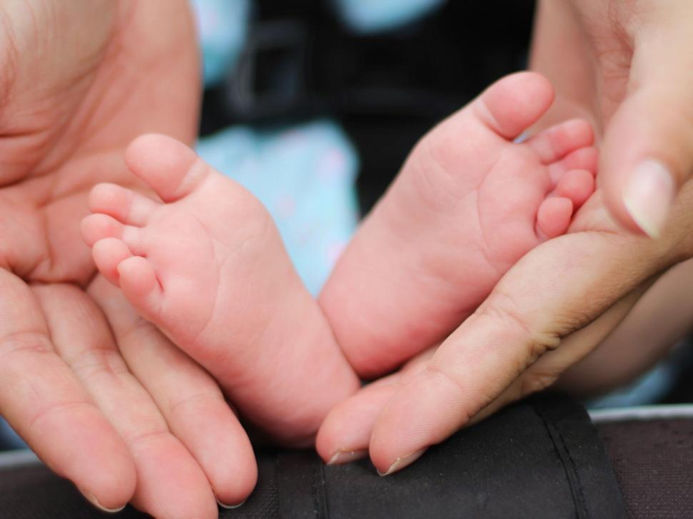 Free Image of Tiny baby feet cradled in parent s hands 