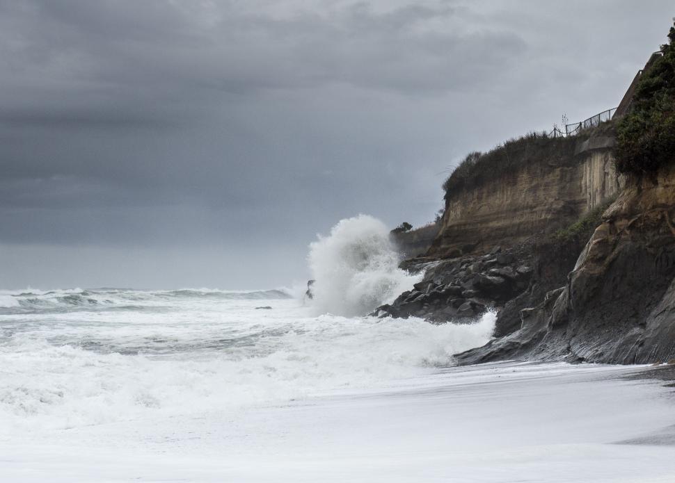 Free Image of Stormy sea waves crashing on cliffside beach 