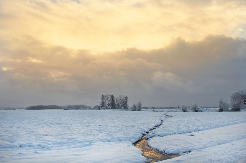 Free Image of Sunset casting glow over snowy field 