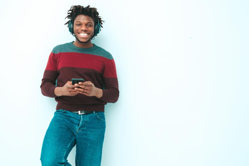 Free Image of A man wearing headphones and holding a phone 