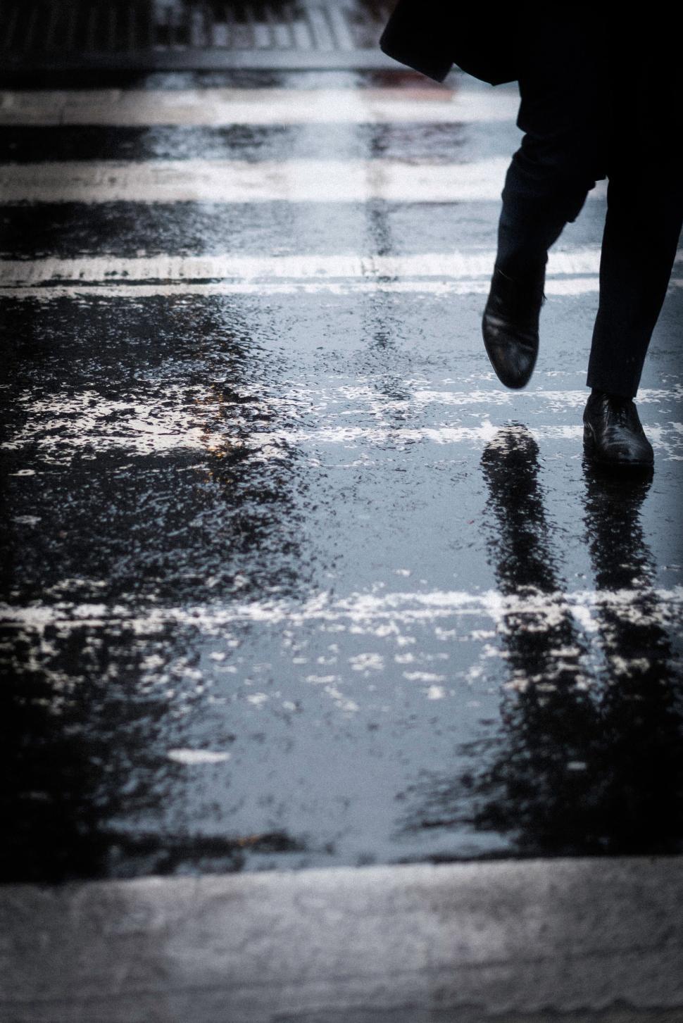 Free Image of Rain-soaked pedestrian crossing urban street 