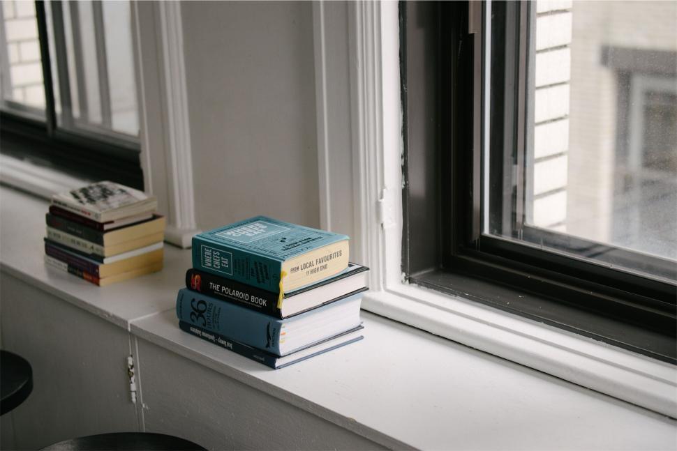 Free Image of Stack of books by a window sill 