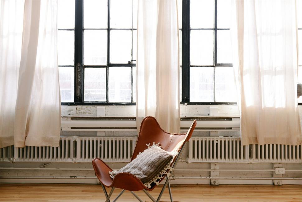 Free Image of Minimalist chair by bright window with curtains 