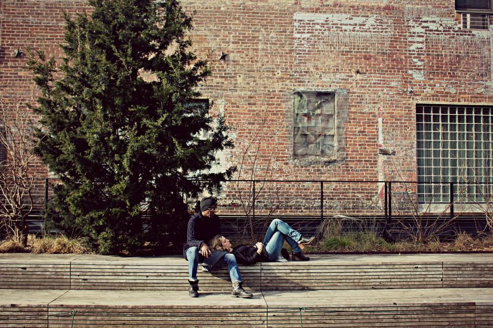 Free Image of Man resting on bench near brick wall 