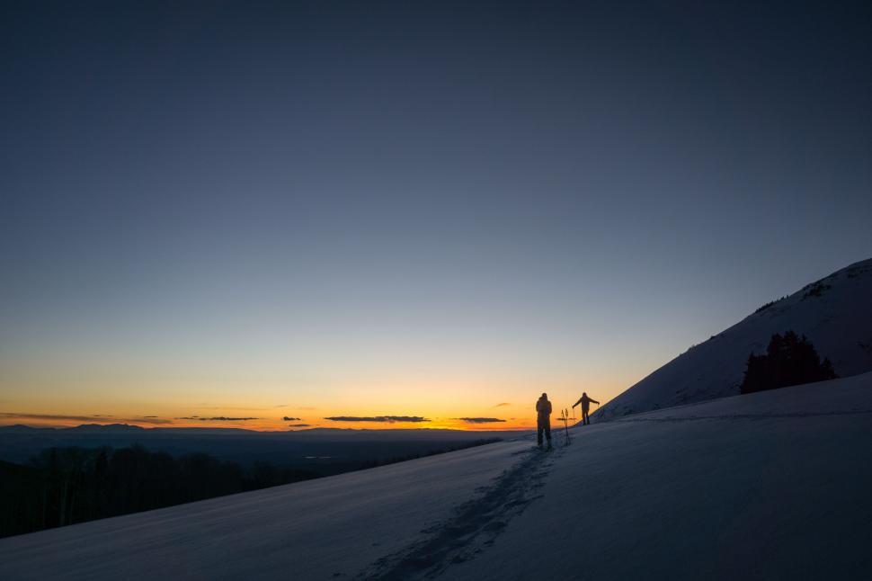 Free Image of Silhouettes trekking on snow at sunset 