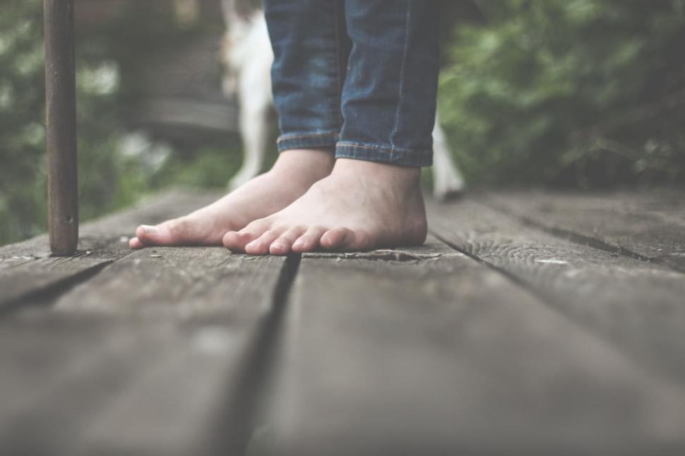 Free Image of Bare feet on a wooden walkway among greenery 