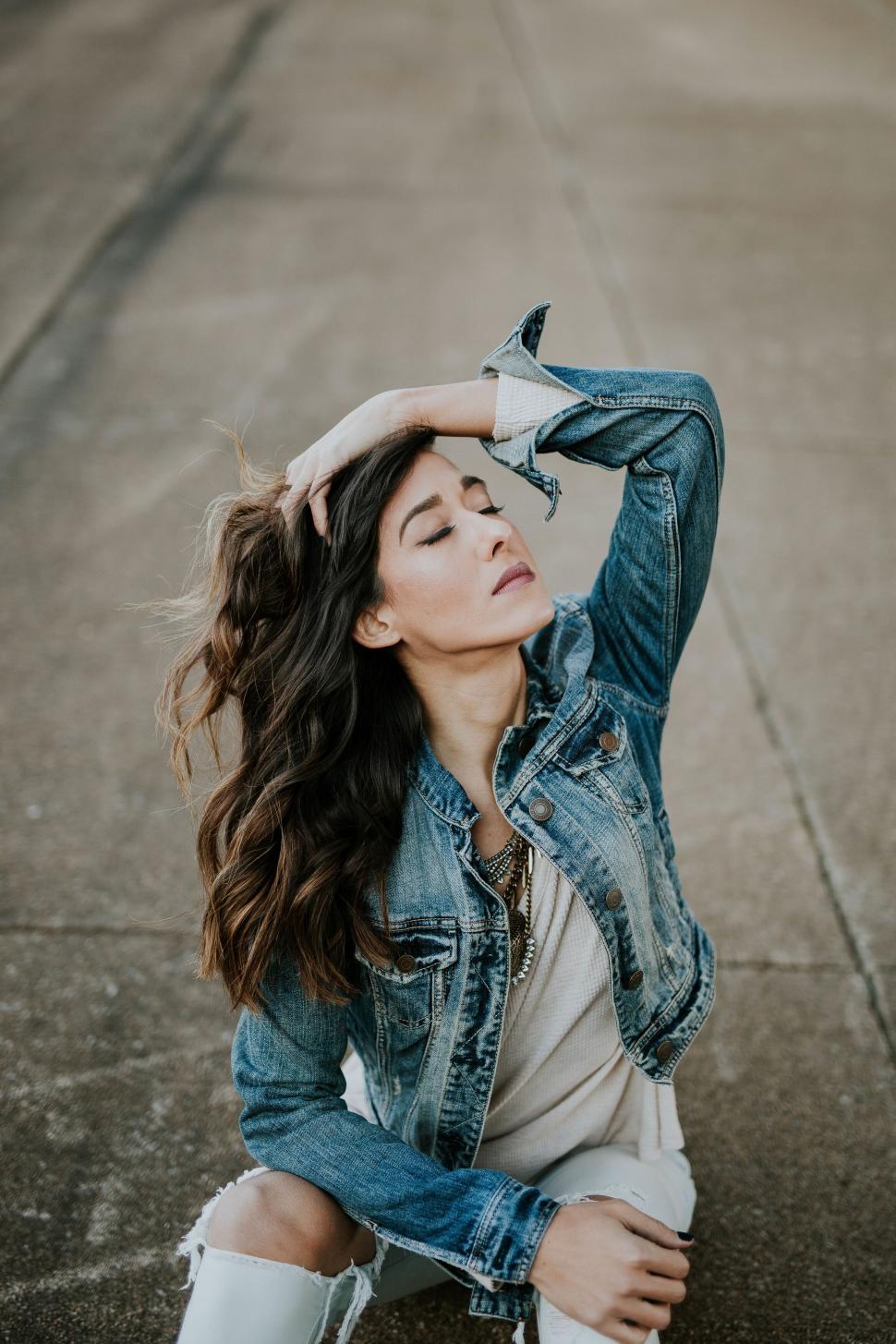 Free Image of Young woman posing in denim jacket on street 