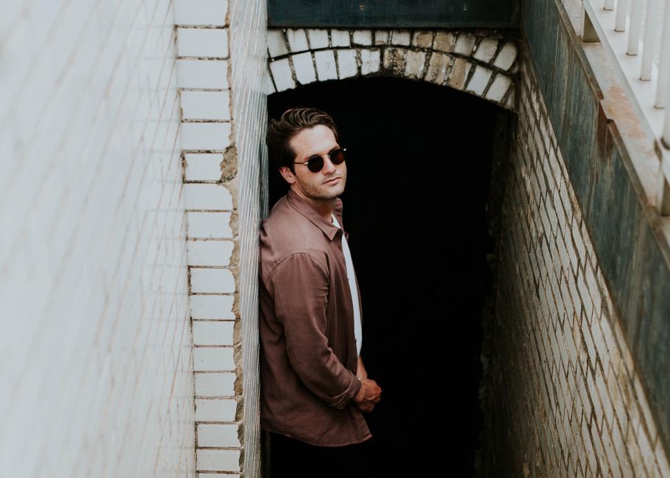 Free Image of Man leaning on tunnel wall in urban setting 
