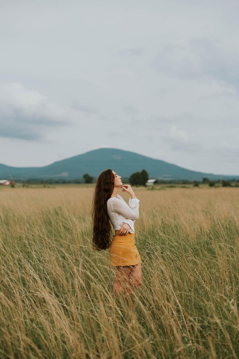 Free Image of Woman in yellow looking at distant mountains 