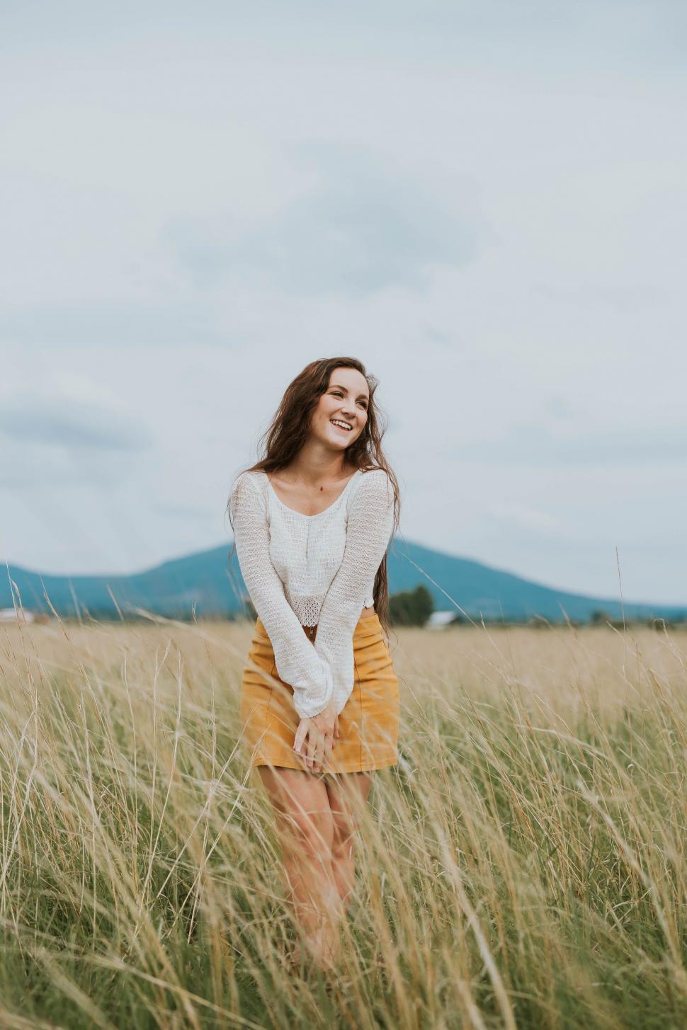 Free Image of Woman in field with mountains in the background 