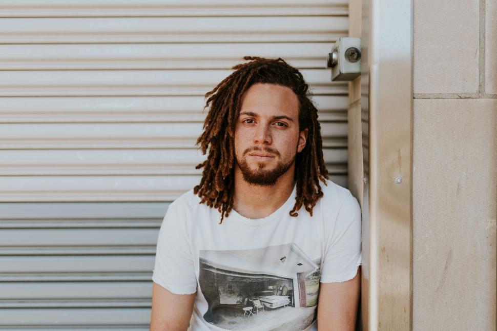 Free Image of Man with dreadlocks posing by wall 