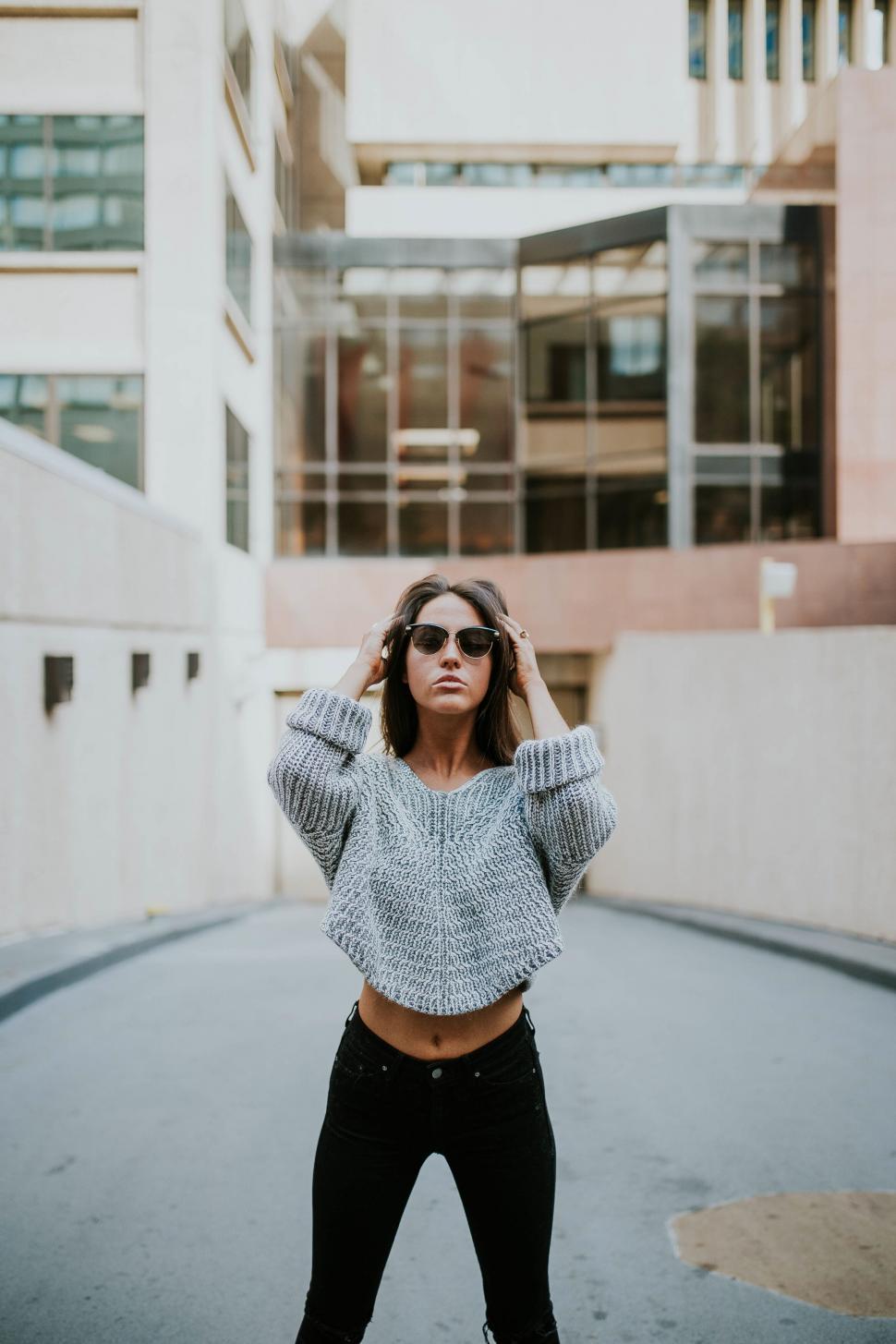 Free Image of Woman in knit sweater posing in urban setting 