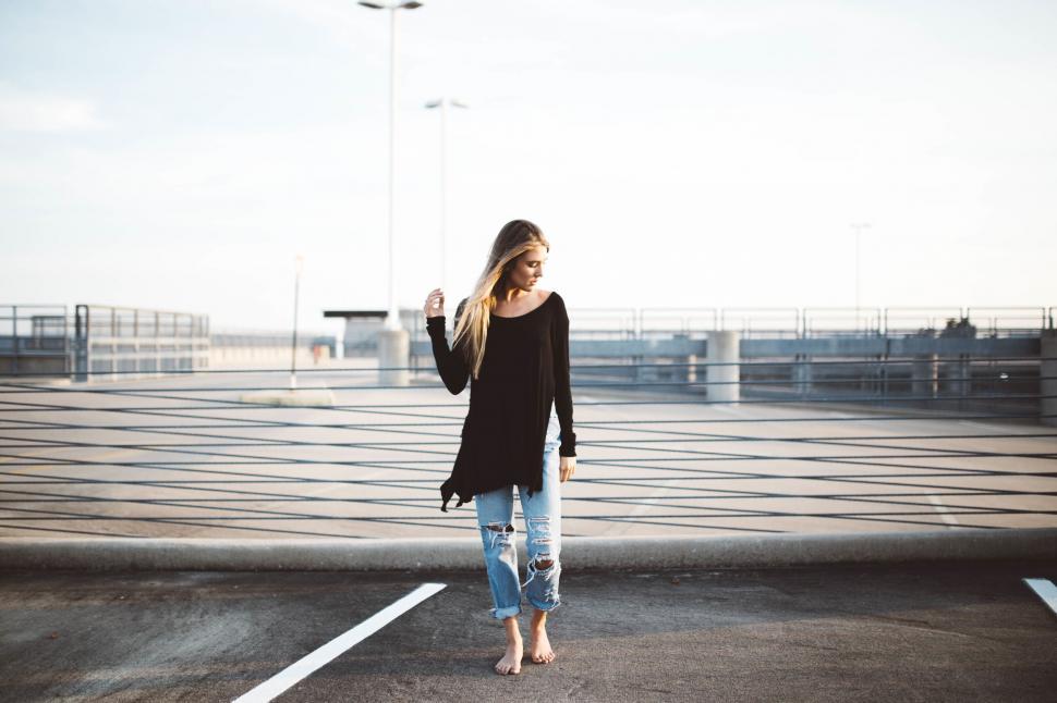 Free Image of Woman in casual wear stands in parking lot 