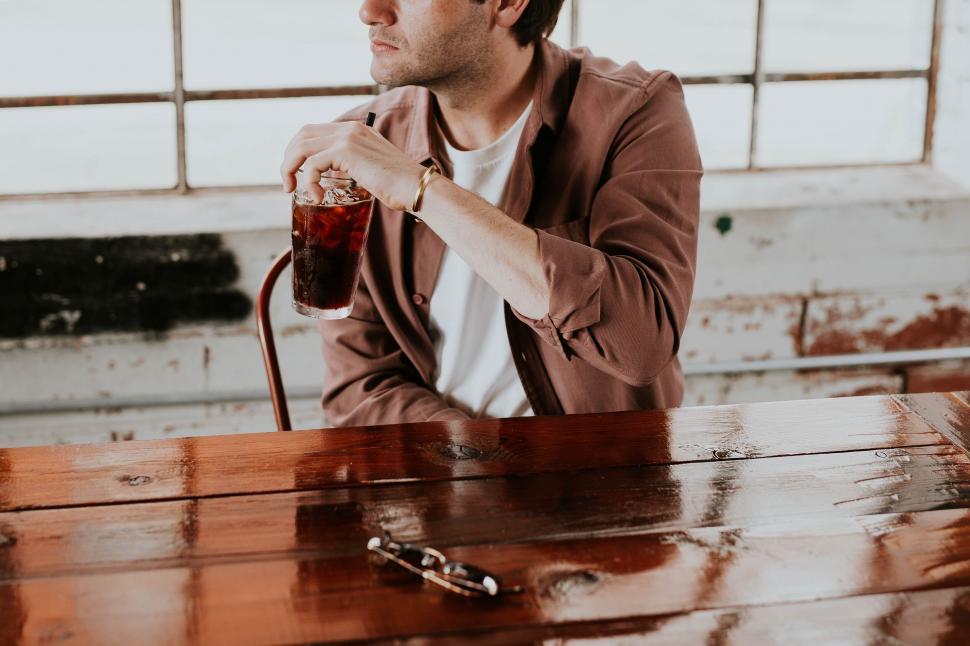 Free Image of Man enjoying a cold drink in a rustic setting 