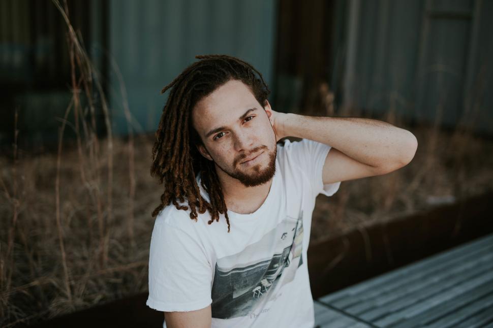 Free Image of Man with dreadlocks sitting outdoors 