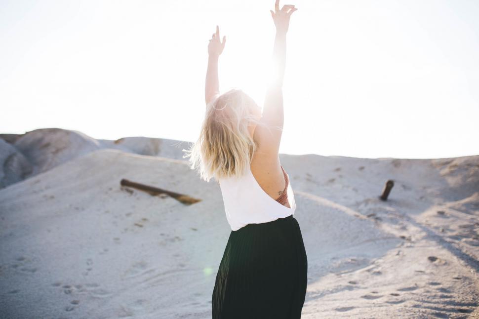 Free Image of Back view of woman raising arms on beach 