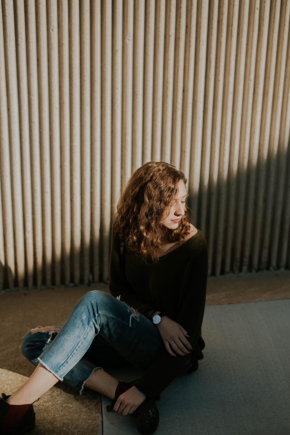 Free Image of Casual woman sitting by corrugated wall 
