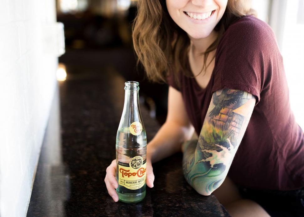 Free Image of Woman smiling with Topo Chico mineral water 