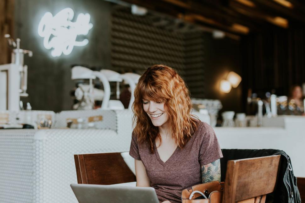 Free Image of Smiling woman using laptop in a cafe 