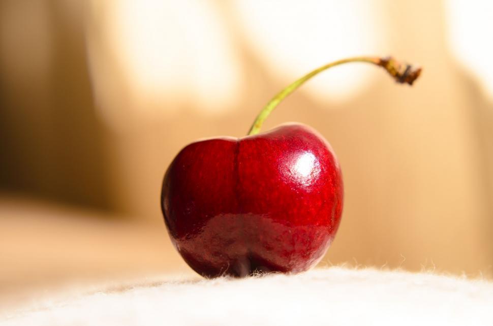 Free Image of Single vibrant cherry on soft fabric 