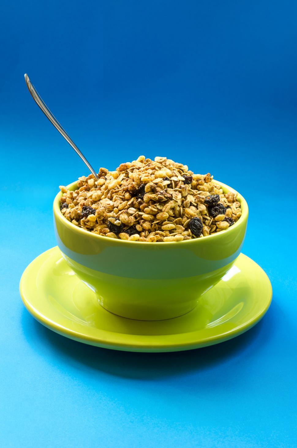 Free Image of Bowl of granola with raisins on vibrant background 