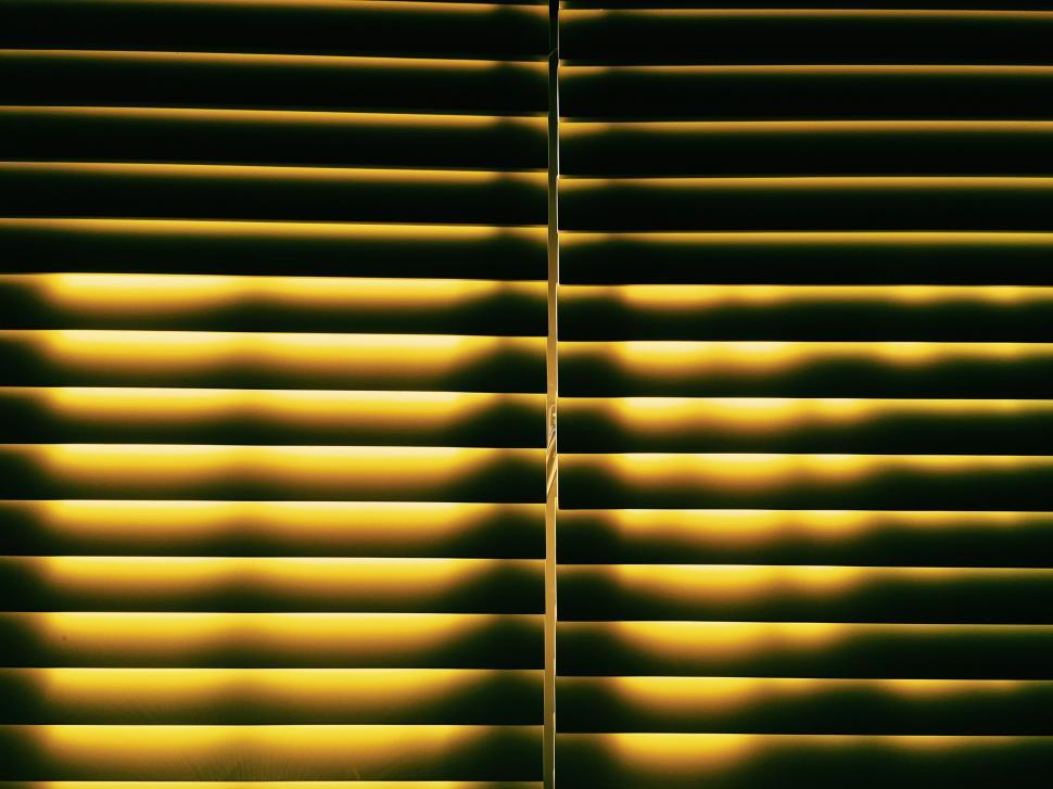 Free Image of Yellow-lighted blinds in a dark room 