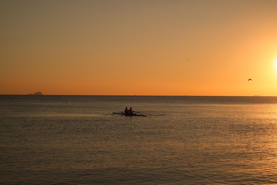 Free Image of Sunset rowing silhouette in serene sea 