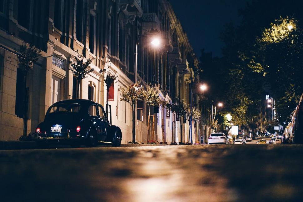 Free Image of Vintage car parked on a city street at night 